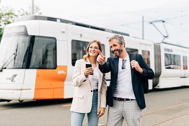 Ein Mann und eine Frau stehen vor einer Straßenbahn.